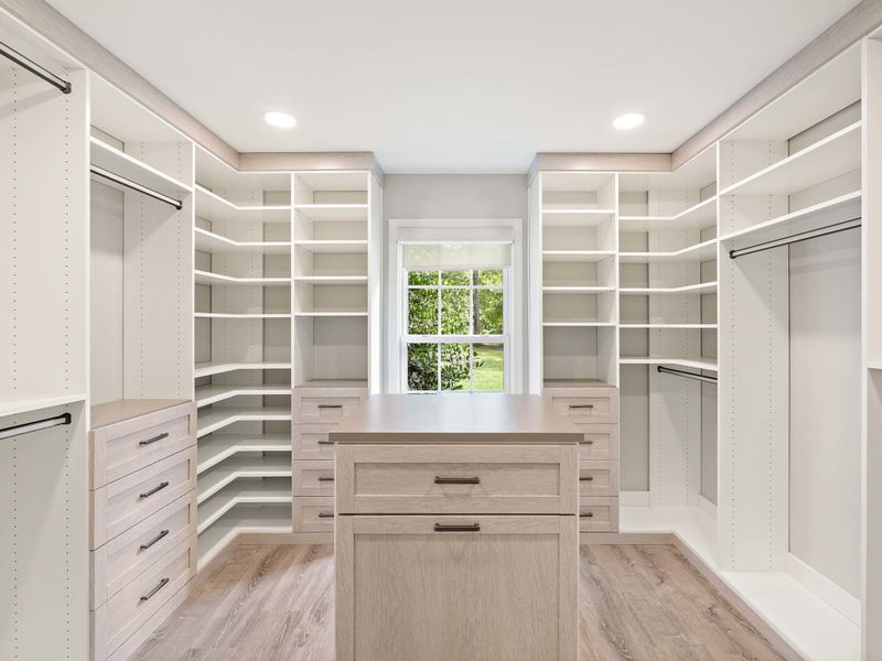 A spacious and organized walk-in closet in the Primary Suite, featuring ample shelving, drawers, and natural light for a luxurious storage solution.