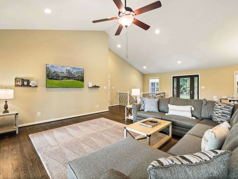 An inviting open-concept living space with a cozy sectional sofa, high ceilings, and a modern kitchen, perfect for gathering and relaxation.