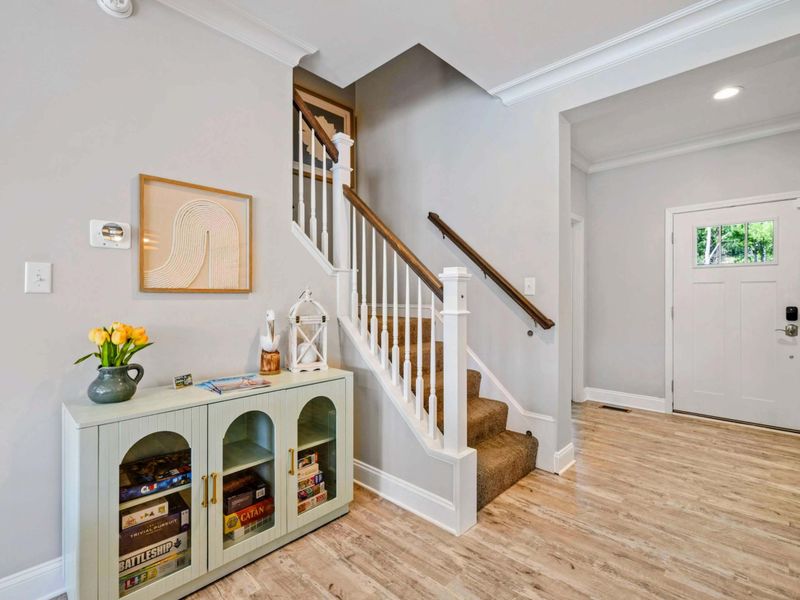 Welcoming entryway with a cozy nook for board games, leading to a charming staircase