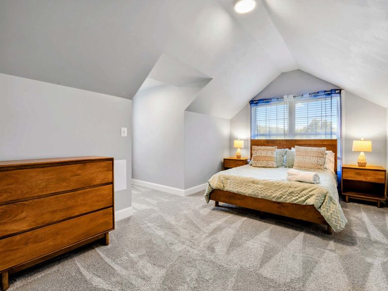 Upper Bedroom - King bed with mid-century walnut furniture tucked under a vaulted dormer ceiling with lake views.