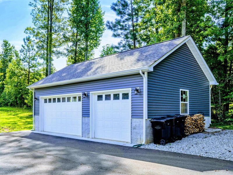 Garage - Detached two-car garage with blue siding to match the home, plus firewood storage on the side.