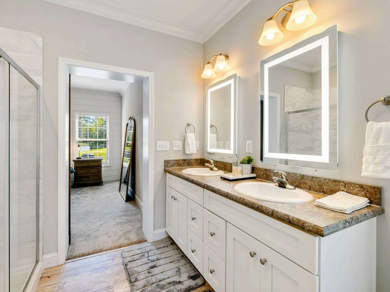Primary Suite Bathroom - Bright and modern ensuite bathroom with a double vanity and a view into the inviting bedroom