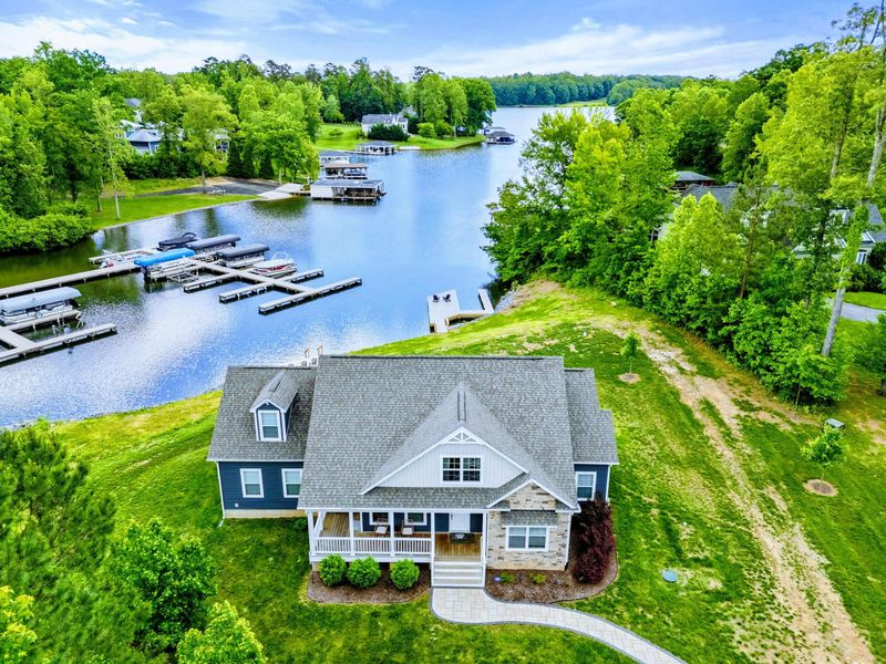 Aerial - Drone view of the home and private dock on the cove, surrounded by lush green trees and neighboring docks.