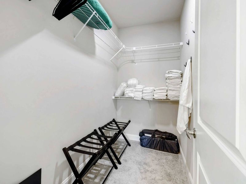 Walk-In Closet - Spacious closet with wire shelving, luggage racks, and extra linens for a comfortable stay.