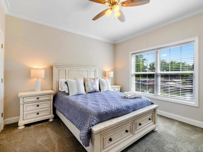 Bedroom - Queen bed with whitewashed farmhouse furniture, blue geometric bedding, and lake views through the window.