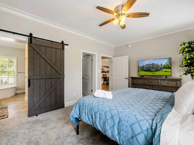 Primary Suite - Spacious bedroom with a king-sized bed, a sliding barn door to the ensuite bathroom, and modern decor