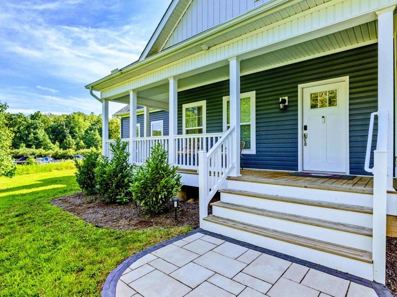 Exterior - Blue craftsman-style home with a covered front porch, white railings, and a paver stone walkway.