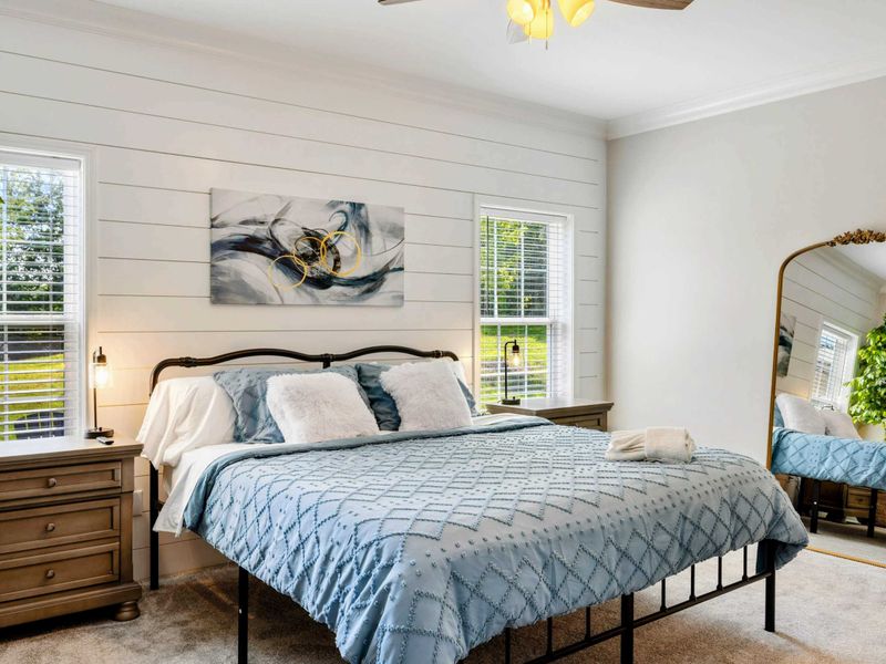 Primary Suite - Cozy and stylish bedroom with a king-sized bed, elegant decor, and a full-length mirror