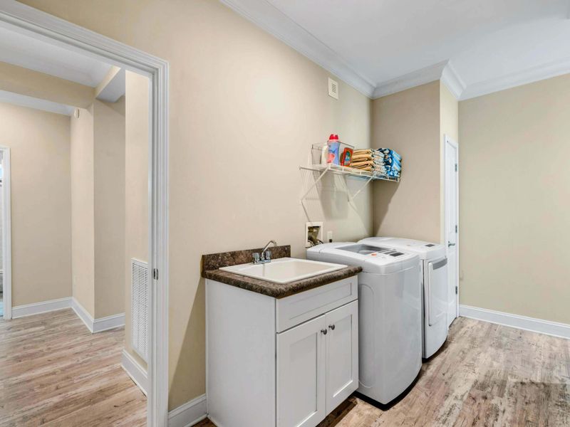 Laundry Room - Full-size washer and dryer with a utility sink, shelf storage, and easy access from the hallway.