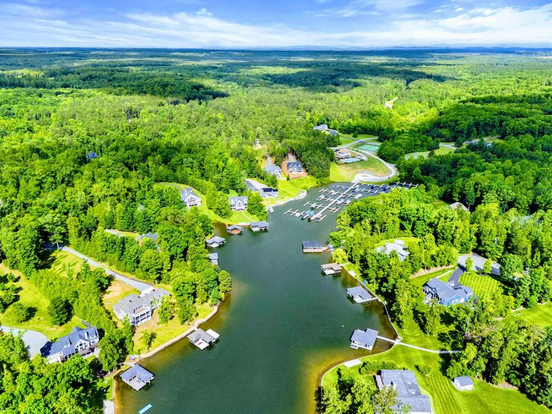Aerial - Panoramic drone shot over the community cove showing waterfront homes, docks, and the Virginia countryside.