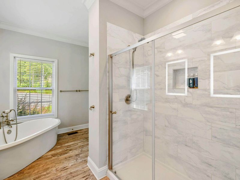 Primary Suite Bathroom - Bright and modern ensuite bathroom with a double vanity and a view into the inviting bedroom