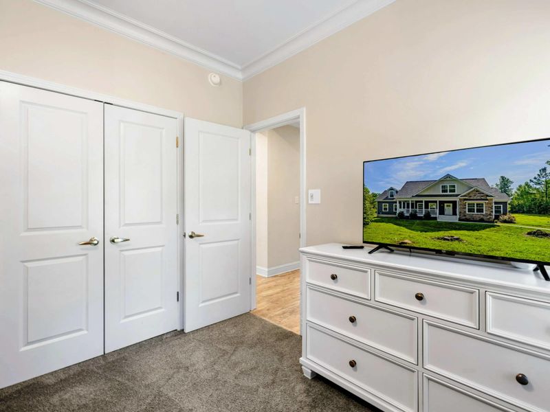 Bedroom - Smart TV on a white dresser with double closet doors and a view through to the hallway.