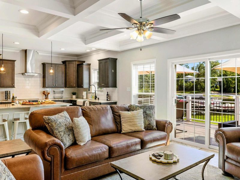 Stylish open-concept living area with comfortable seating, a modern kitchen, and access to a sunny outdoor deck