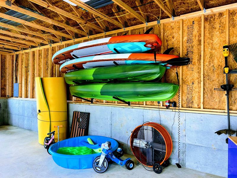 Garage Interior - Kayak and paddleboard storage rack with pool floats and outdoor toys for lake adventures.
