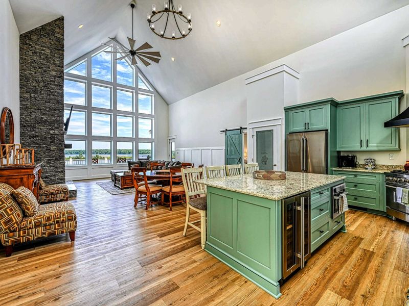 Beautiful open kitchen and living area with vaulted ceilings, a large island, and stunning floor-to-ceiling windows showcasing lake views