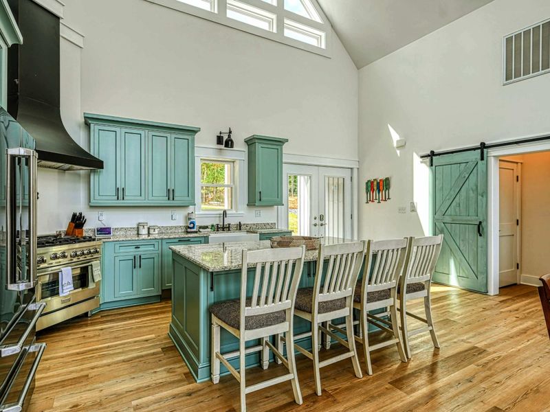 Spacious and inviting kitchen with a large island, bar seating, and elegant green cabinets, perfect for family gatherings