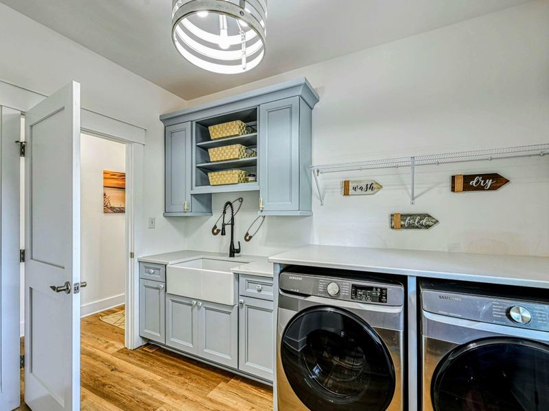 Fully equipped laundry room with modern appliances, ample storage, and a farmhouse sink for added convenience