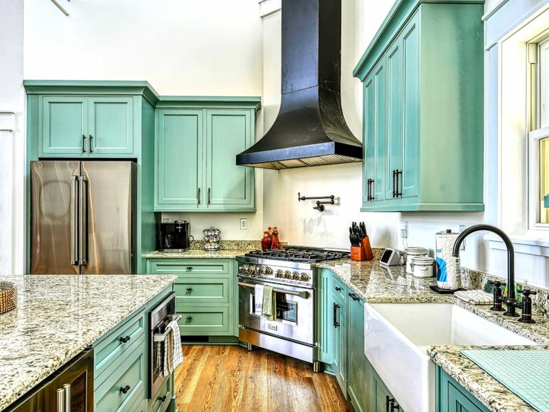 Beautifully designed kitchen with a farmhouse sink, high-end stainless steel appliances, and elegant green cabinets
