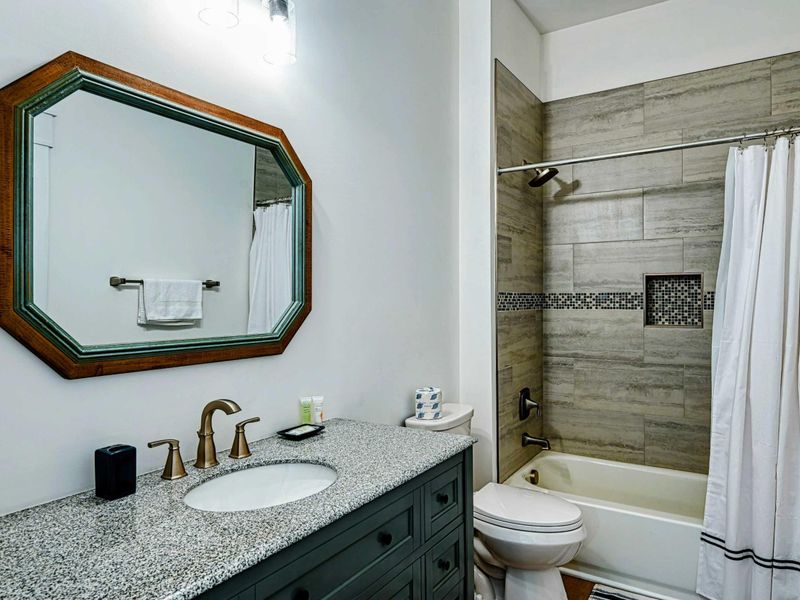 Modern bathroom with a granite countertop, stylish tiled shower, and elegant fixtures for a comfortable stay