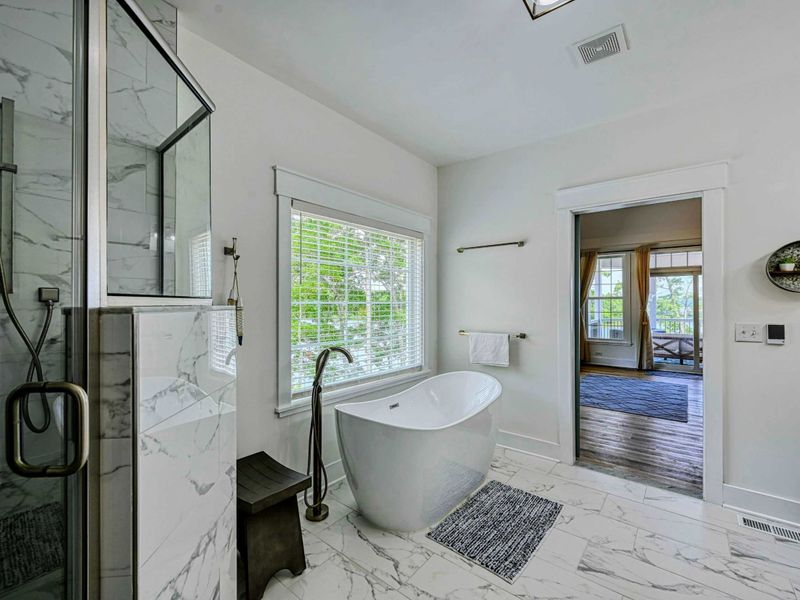 Luxurious bathroom with a freestanding tub, marble flooring, and plenty of natural light, offering a relaxing retreat