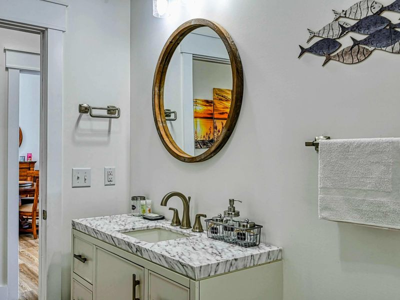Chic bathroom with a marble vanity, round mirror, and tasteful decor, providing a touch of elegance