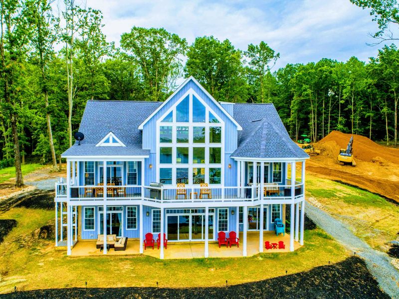 Charming lakefront home with expansive windows and multiple balconies, offering a bright and inviting space for guests