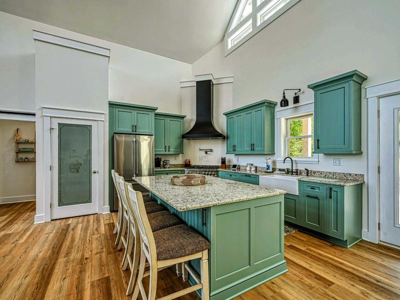 Spacious and modern kitchen with a large island, stylish green cabinetry, and plenty of natural light, perfect for cooking and entertaining