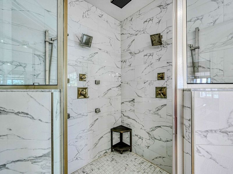Elegant marble-tiled shower with multiple showerheads and luxurious fixtures for a spa-like experience