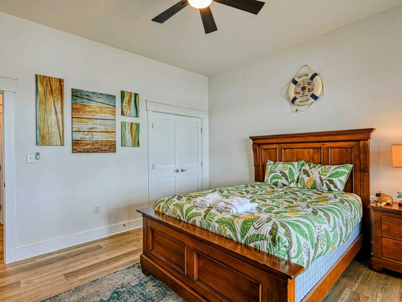 Cozy bedroom with tropical-themed bedding, wooden furniture, and tasteful wall art, creating a relaxing retreat