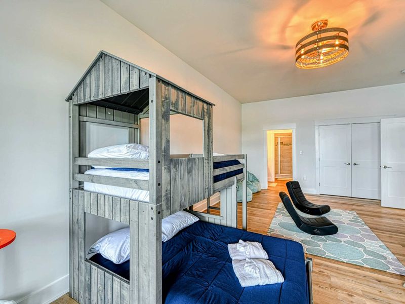 Bright and playful kids' room with unique house-shaped bunk beds and comfortable seating, perfect for a fun stay