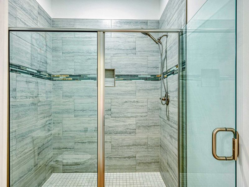 Spacious walk-in shower with sleek tile work and modern fixtures, providing a luxurious bathing experience