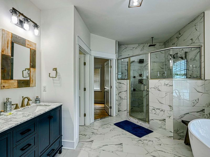 Luxurious bathroom featuring a marble-tiled shower, double vanity, and elegant freestanding tub for a spa-like experience