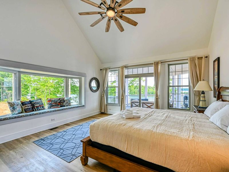 Bright and airy bedroom with vaulted ceilings, a cozy window seat, and private access to a balcony with stunning views