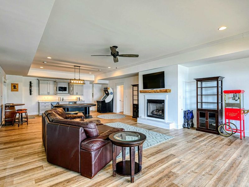 Entertainment room with cozy seating, a fireplace, arcade games, and a kitchenette, perfect for relaxing and having fun