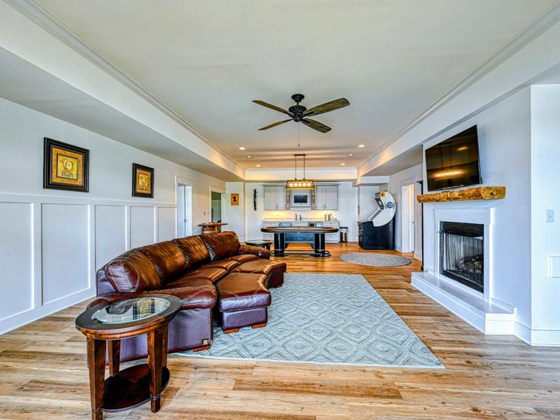Spacious lounge area with a leather sectional, fireplace, and game setup, offering a perfect spot for relaxation and entertainment