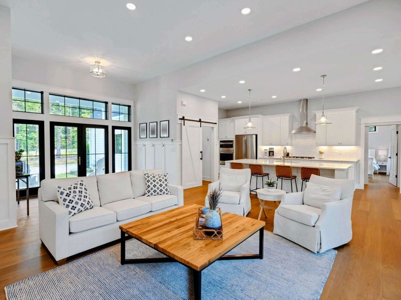 Bright and airy living room featuring a cozy fireplace, stylish furnishings, and large windows for natural light.
