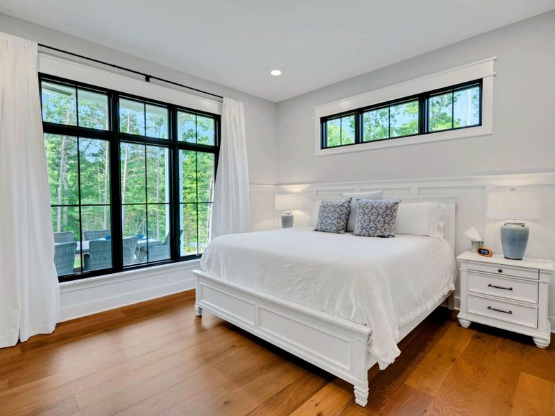 Bright and serene bedroom featuring a luxurious king bed, large windows with stunning outdoor views, and modern decor.