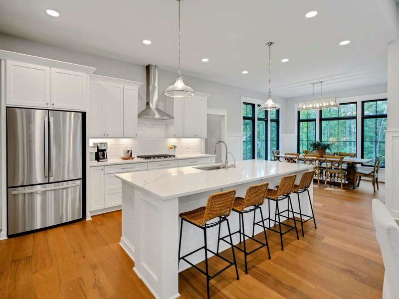 Modern kitchen with a large quartz island, stainless steel appliances, farmhouse-style barn doors, and seating for four.