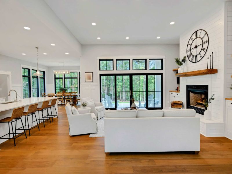 Bright and airy living room featuring a cozy fireplace, stylish furnishings, and large windows for natural light.