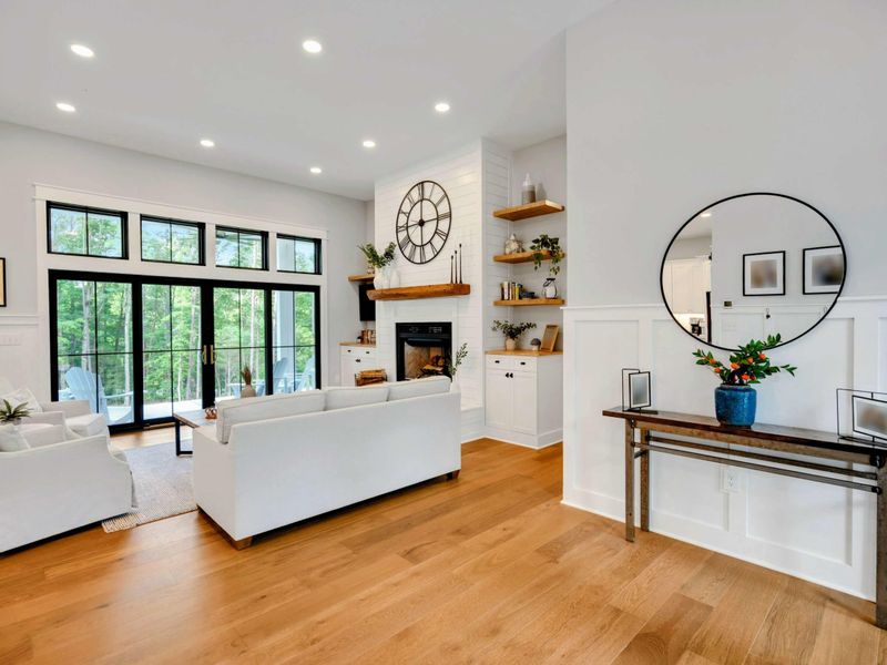 Bright and airy living room featuring a cozy fireplace, stylish furnishings, and large windows for natural light.