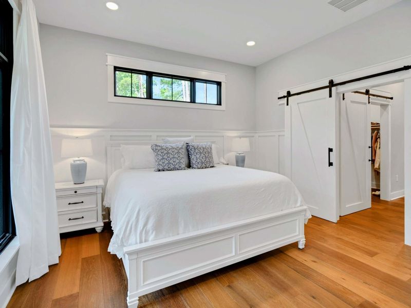 Bright and serene bedroom featuring a luxurious king bed, large windows with stunning outdoor views, and modern decor.
