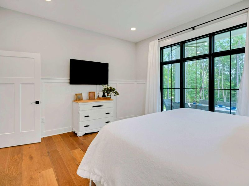 Bright and serene bedroom featuring a luxurious king bed, large windows with stunning outdoor views, and modern decor.