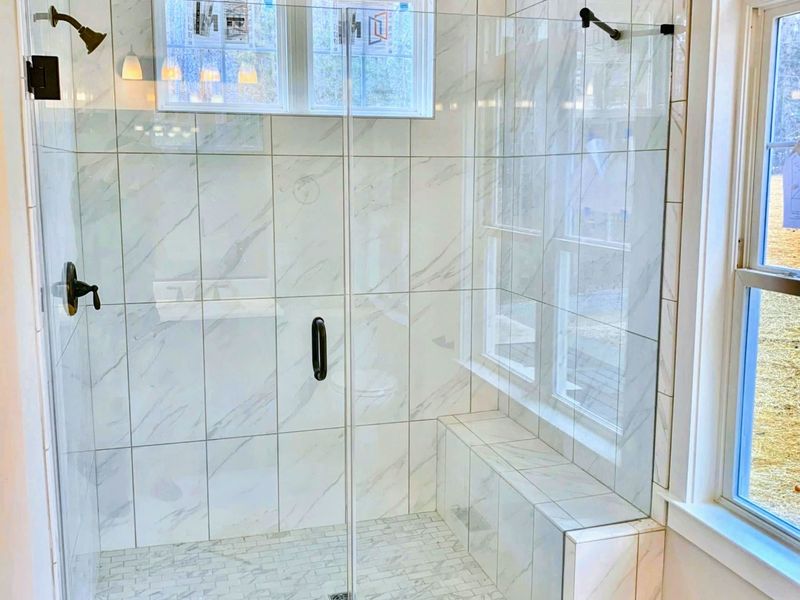 Suite 1 Bath - A large glass shower and high-end tile give the main-level suite's private bath a clean, spa-like finish.