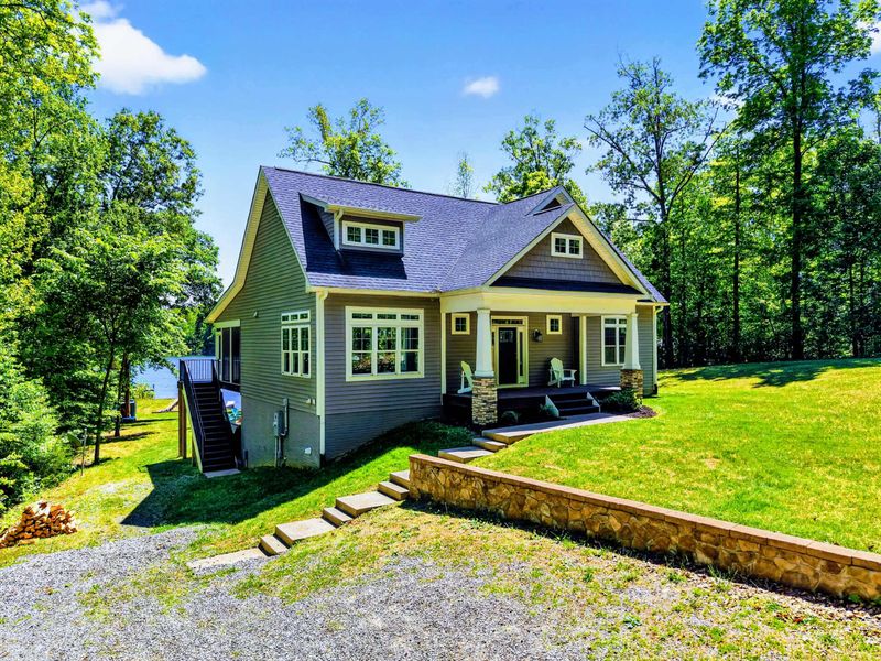 Front Exterior - Stone steps and a craftsman porch greet you off the gravel drive, lake just beyond the trees.