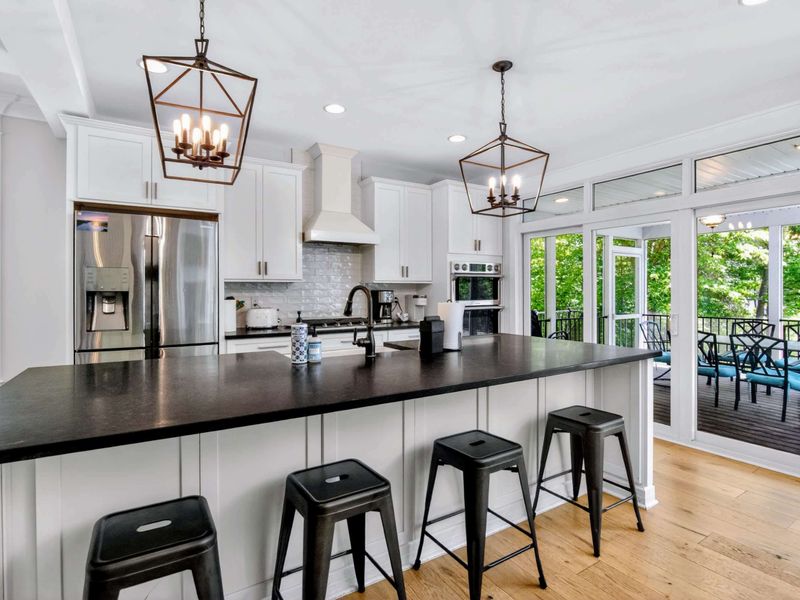 Kitchen - Ten-foot soapstone island, lantern pendants, and a wall of glass opening to the screened porch, this is where the day starts and ends.
