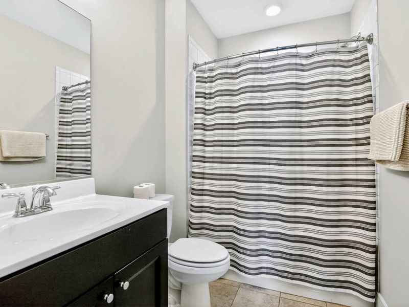 Suite 2 Bath - Dark vanity against soft gray walls keeps things simple and clean for the next round of guests.
