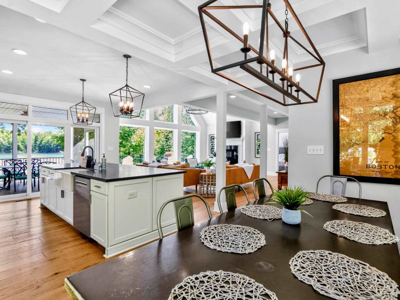 Dining Room - Long farmhouse table under lantern chandelier, lake glinting past the kitchen, the seat everyone wants.
