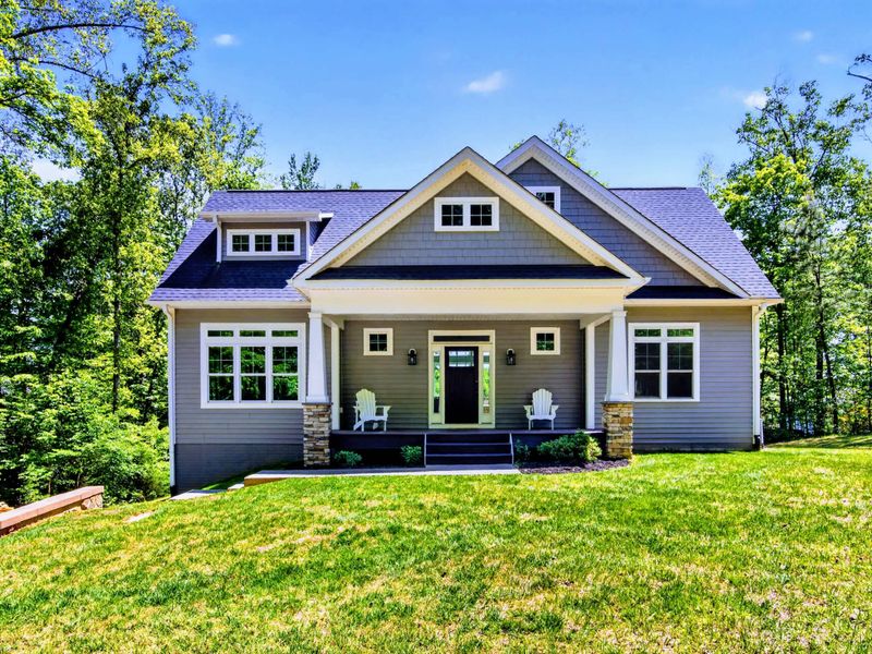 Front Exterior - Craftsman porch with rocking chairs and stone columns, the kind of arrival that signals you've left town behind.