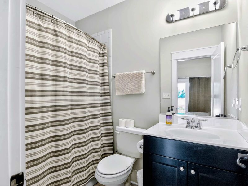 Suite 3 Bath - Dark vanity and striped curtain keep this guest bath tidy and ready after a day on the water.