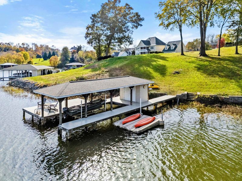 Lakefront dock with covered boat storage and kayaks, offering easy access to water activities